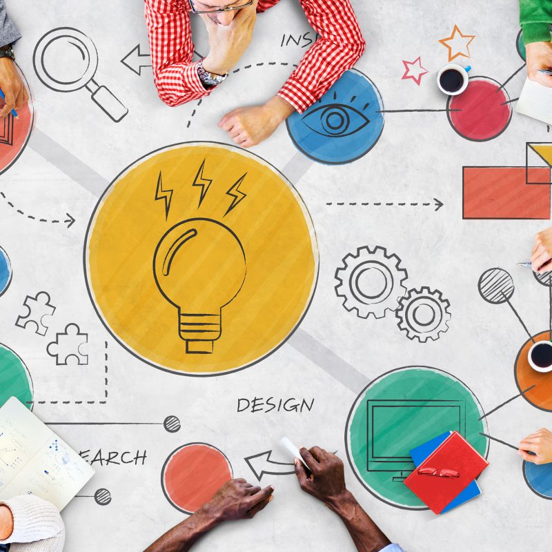 Mesa com brainstorm de ideias e pessoas desenvolvendo a criatividade em torno