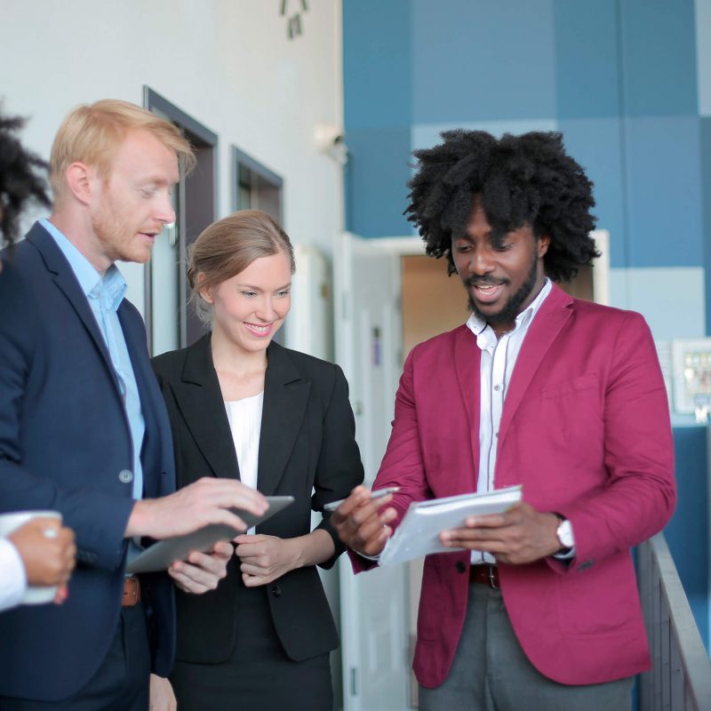 4 pessoas em ambiente de trabalho vendo um caderno e sorrindo